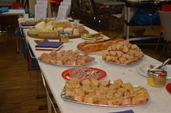 A table is set with many plates and trays. On them you can find different delicious French dishes, like cheese.